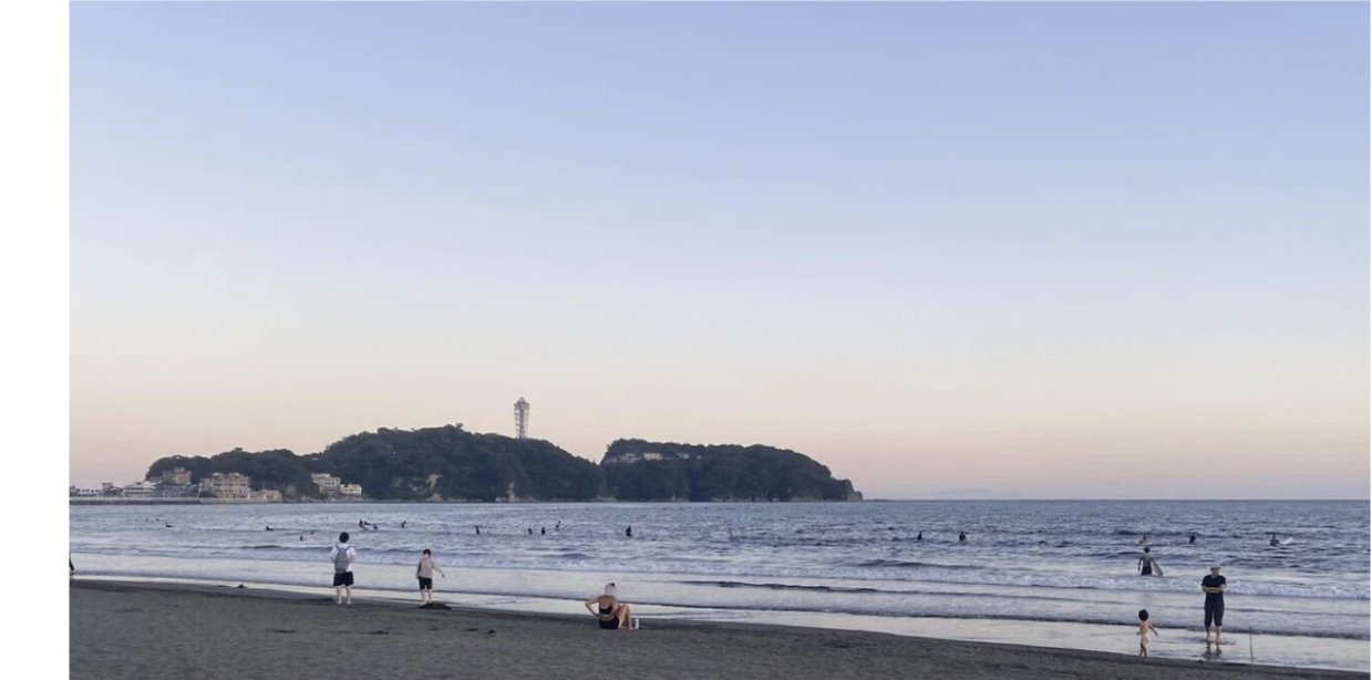 夕暮れの江ノ島の海岸で人々が波打ち際で過ごす写真