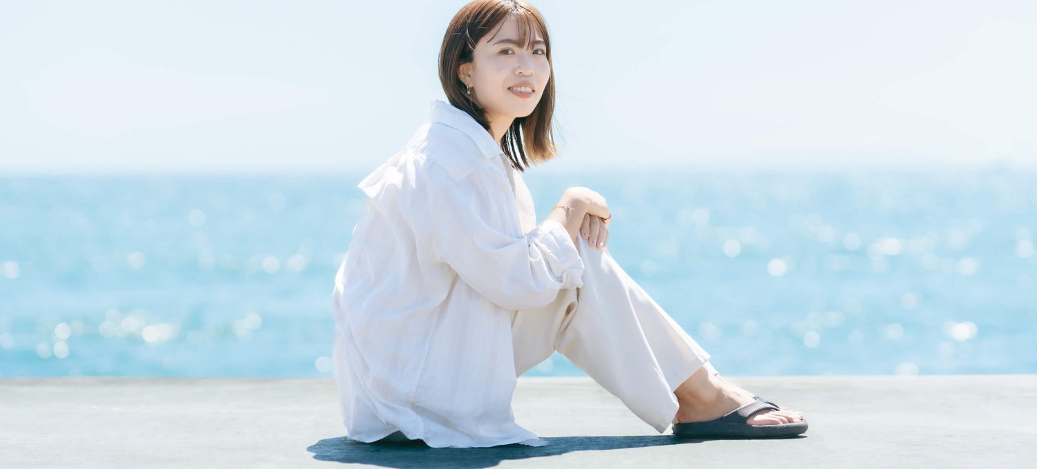 海を背に座り微笑むmomokaさん