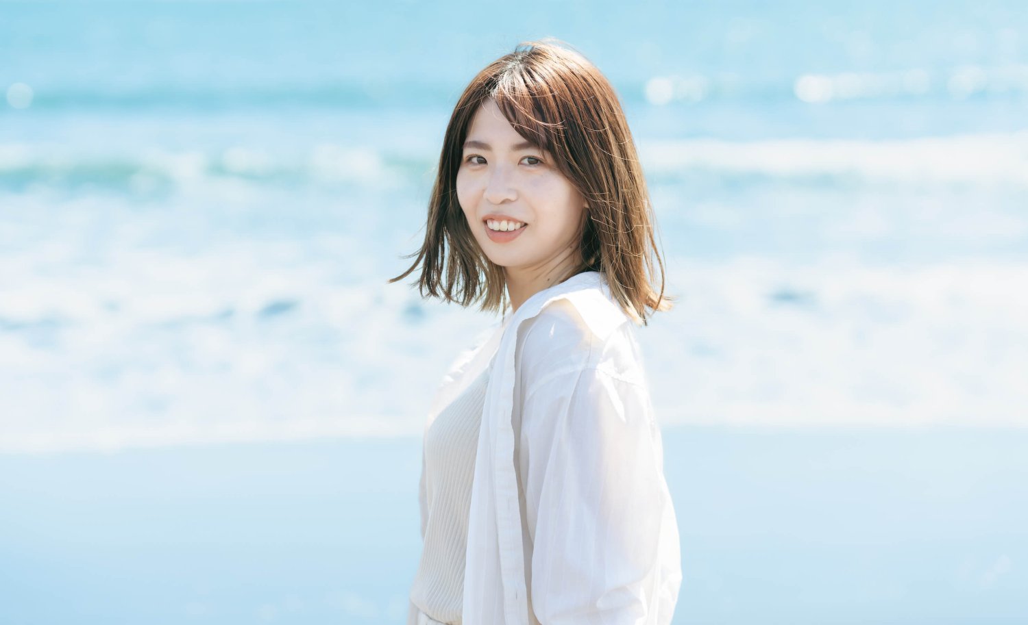 海を背に振り返り微笑むmomokaさん