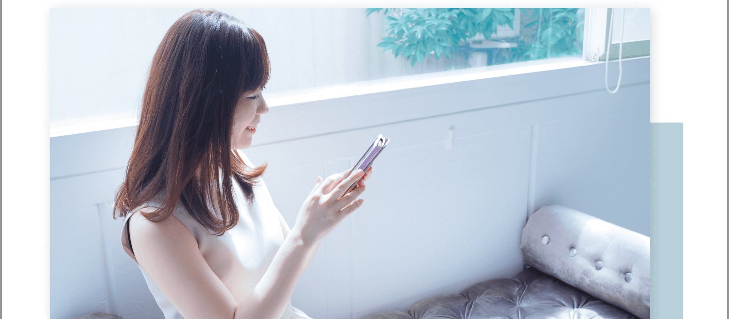 窓辺のソファでスマートフォンを見て微笑む女性