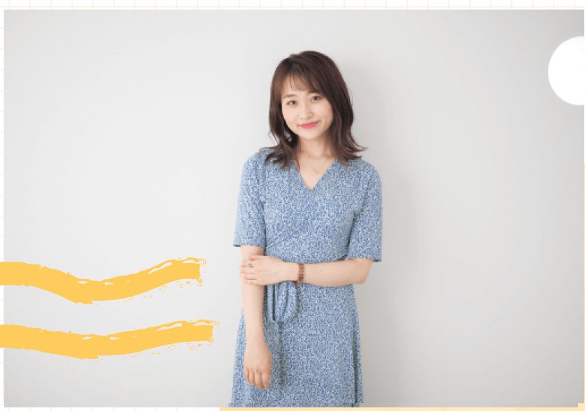 グレーの壁の前に立つ青い花柄の服の女性（全身）