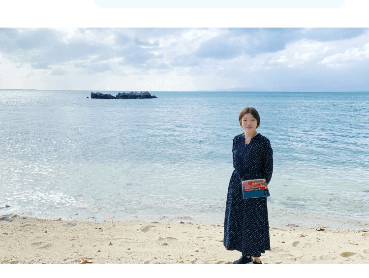砂浜の海辺に立つ小山志織さん(紺色ドット柄ワンピース)
