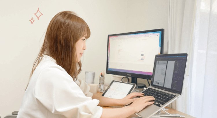 デスクで2台のモニターとノートパソコンに向かって作業するsayakaさん