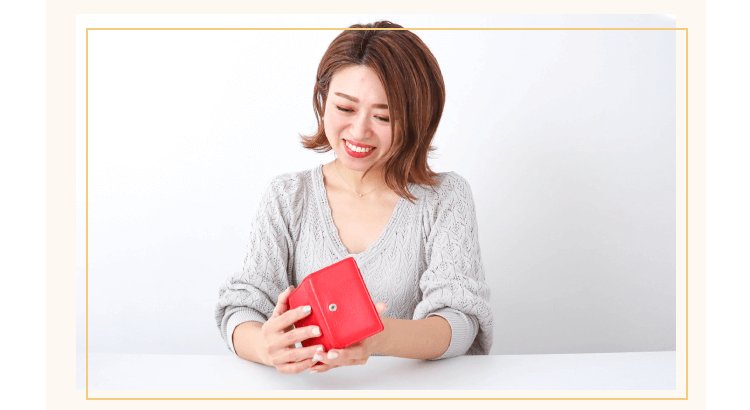 赤い財布を手に微笑む女性