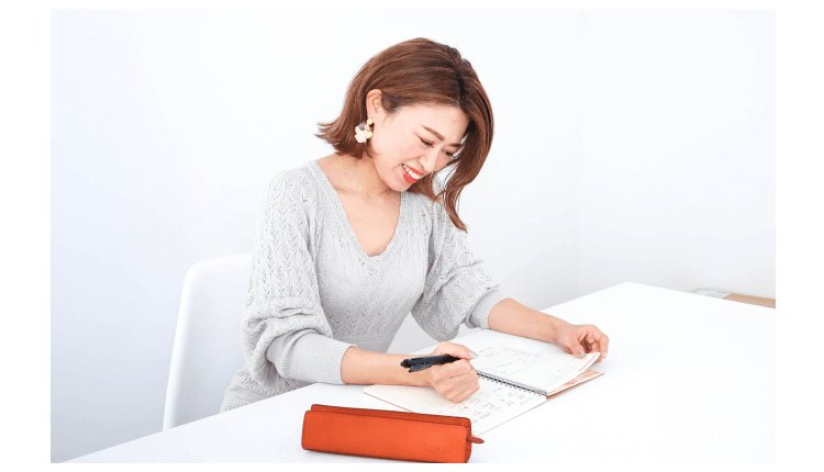 ペンを持ってノートに書き込む女性