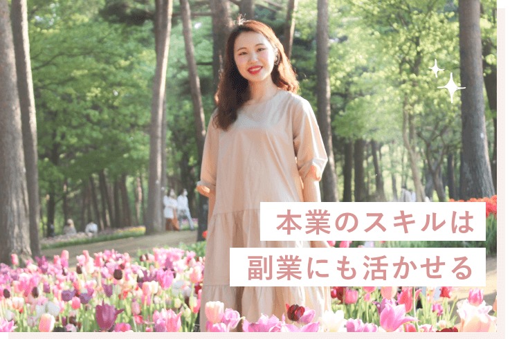 緑豊かな遊歩道のチューリップ畑に立つシホさん。本業のスキルは副業にも活かせる、という文言入り