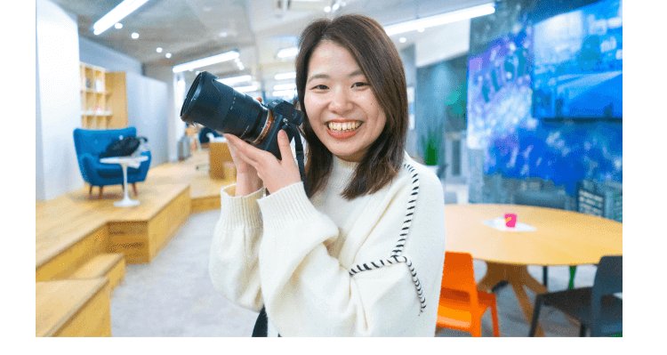 笑顔でカメラを構えるかんなさん（コワーキングスペース内）