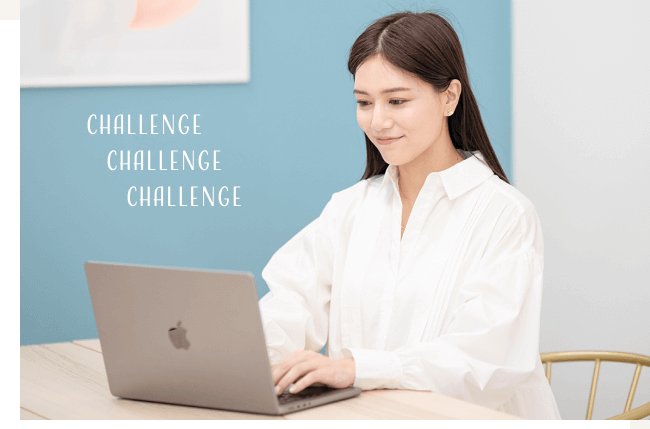 青い壁のオフィスでノートPCに向かう石井さんの写真(背景に「CHALLENGE」の文字装飾)