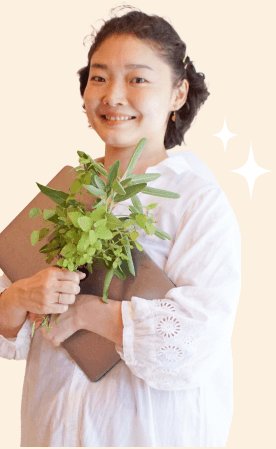 ノートと葉物植物を抱えて微笑む白シャツ姿のちえこさん、キラキラ装飾つき（After）