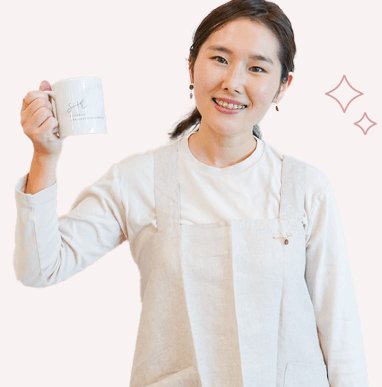 マグカップを掲げて微笑む萌さん