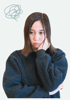 頬杖をつき俯き、頭上に曇った思考の落書きが浮かぶ紺ニット姿のみづきさん（Before）