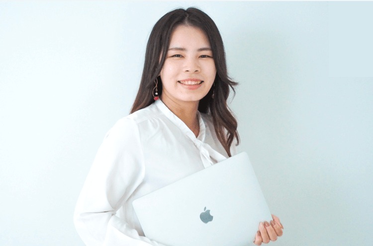 ノートパソコンを抱えて微笑むこにまるさんのポートレート