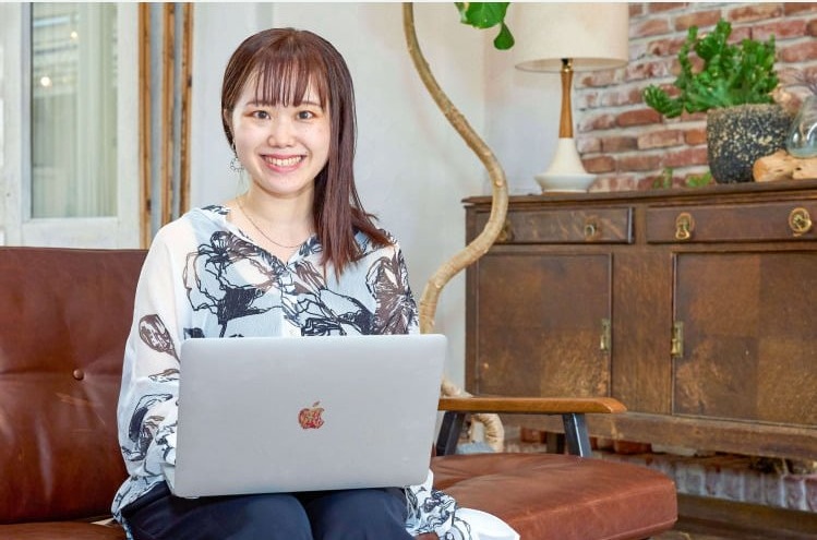 ソファでノートPCに向かい微笑む愛弓さん