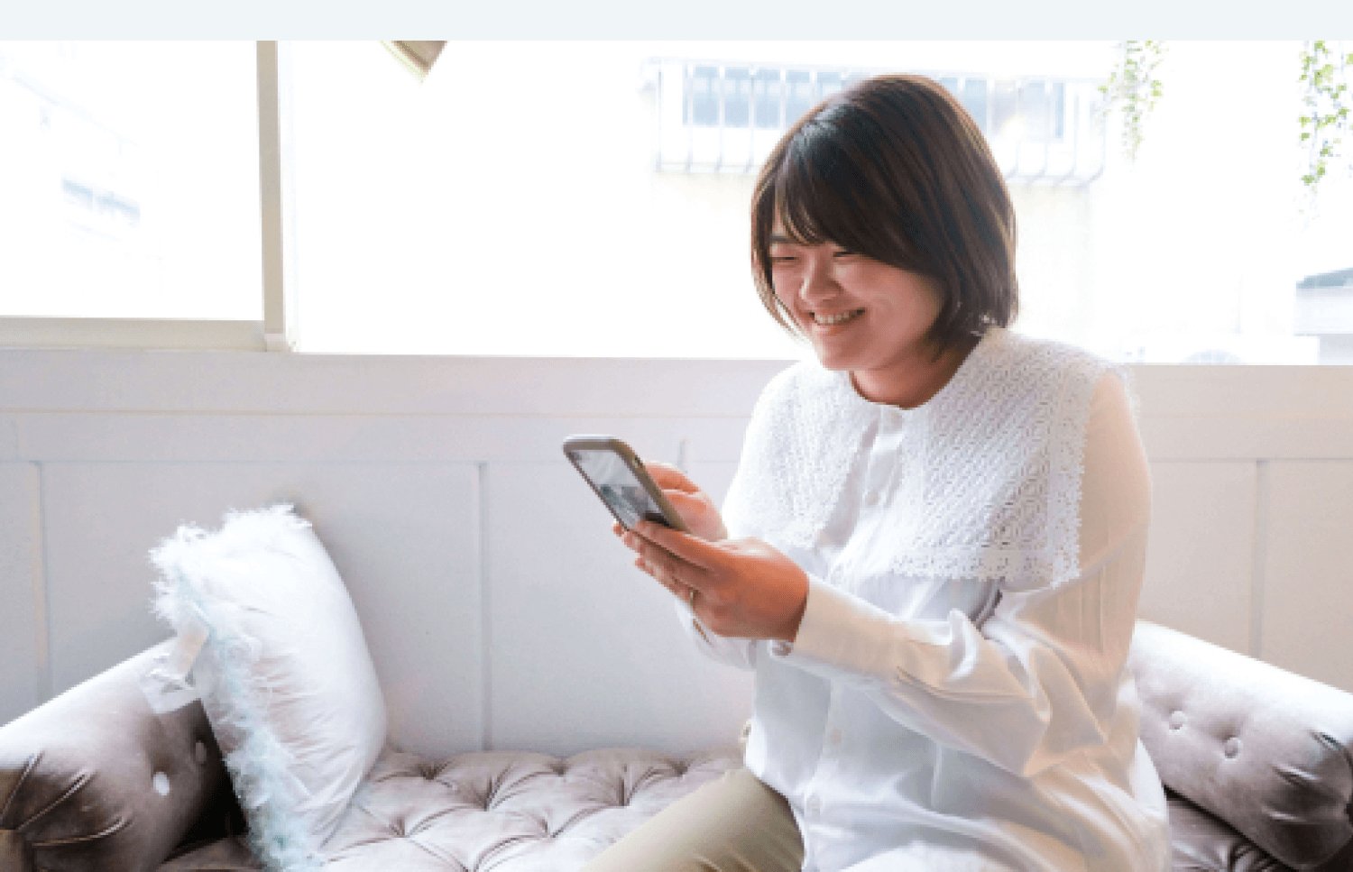 ソファでスマートフォンを見て微笑むりょうこさん