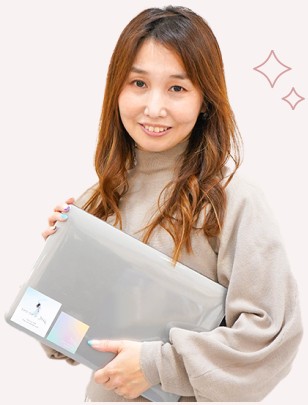ノートPCケースを抱えて微笑む女性（After、キラキラ装飾付き）
