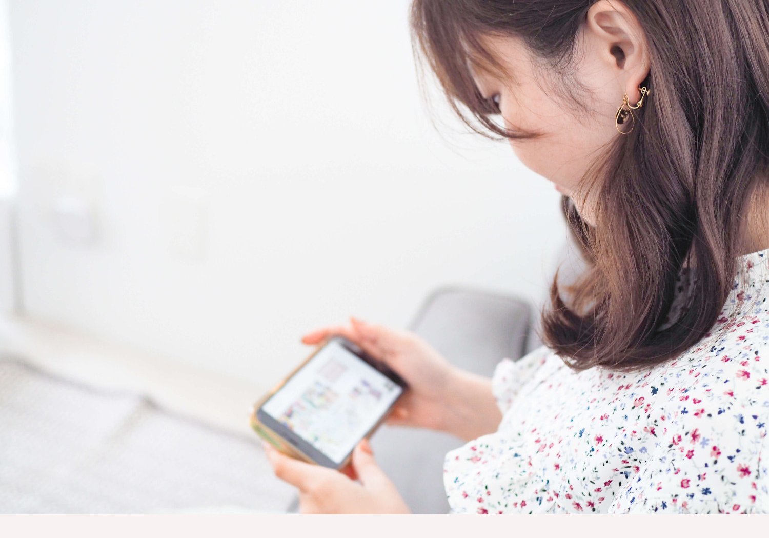 ソファでノートパソコンとスマートフォンを手に微笑むさほさん