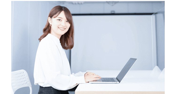 白いテーブルでノートPCに向かい振り返って微笑む女性