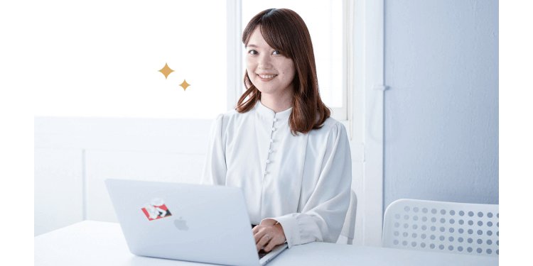 白いテーブルでノートPCに向かい微笑む女性