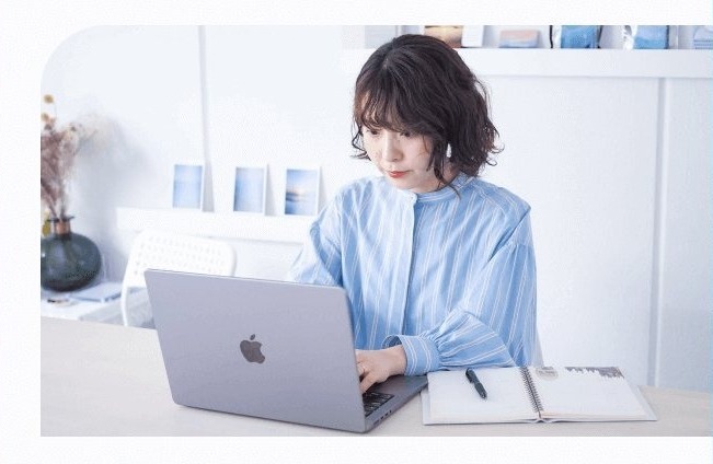 デスクで手帳に書き込みながらノートパソコンに向かう萌さん