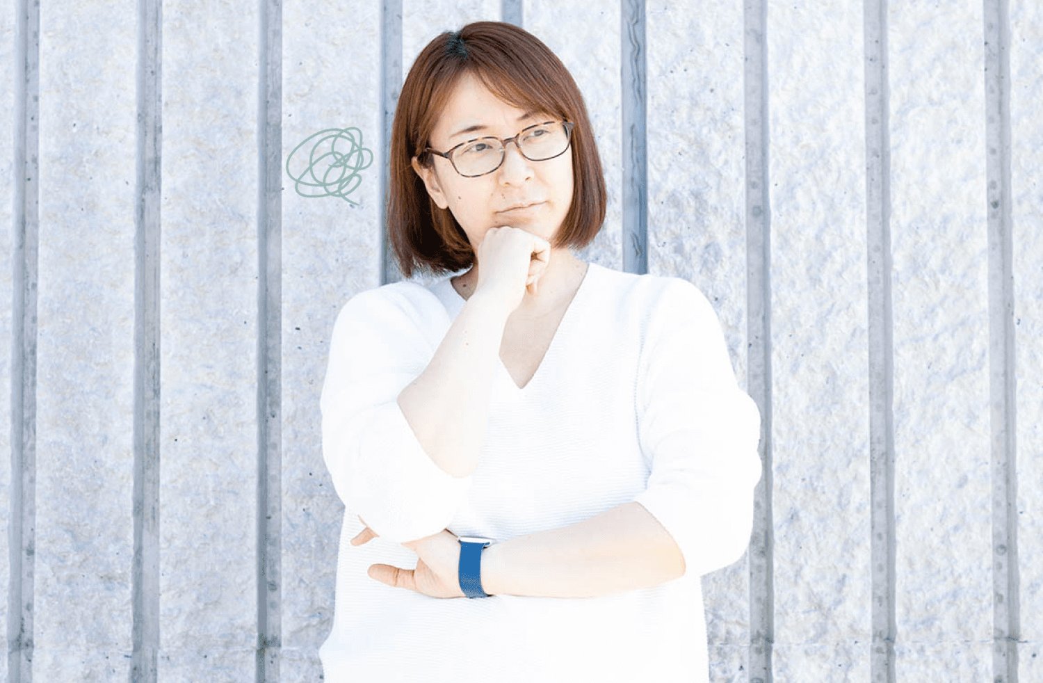 蛇腹壁を背景に顎に手を当て考え込む美緒さん