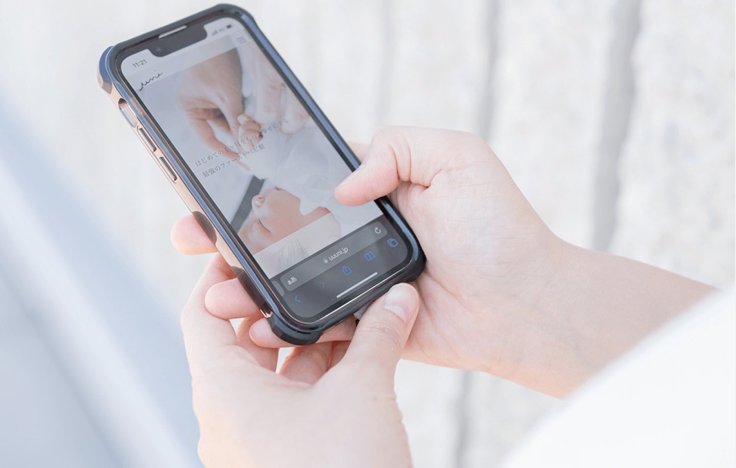 スマートフォンでベビー服ブランドのWebサイトを操作する両手