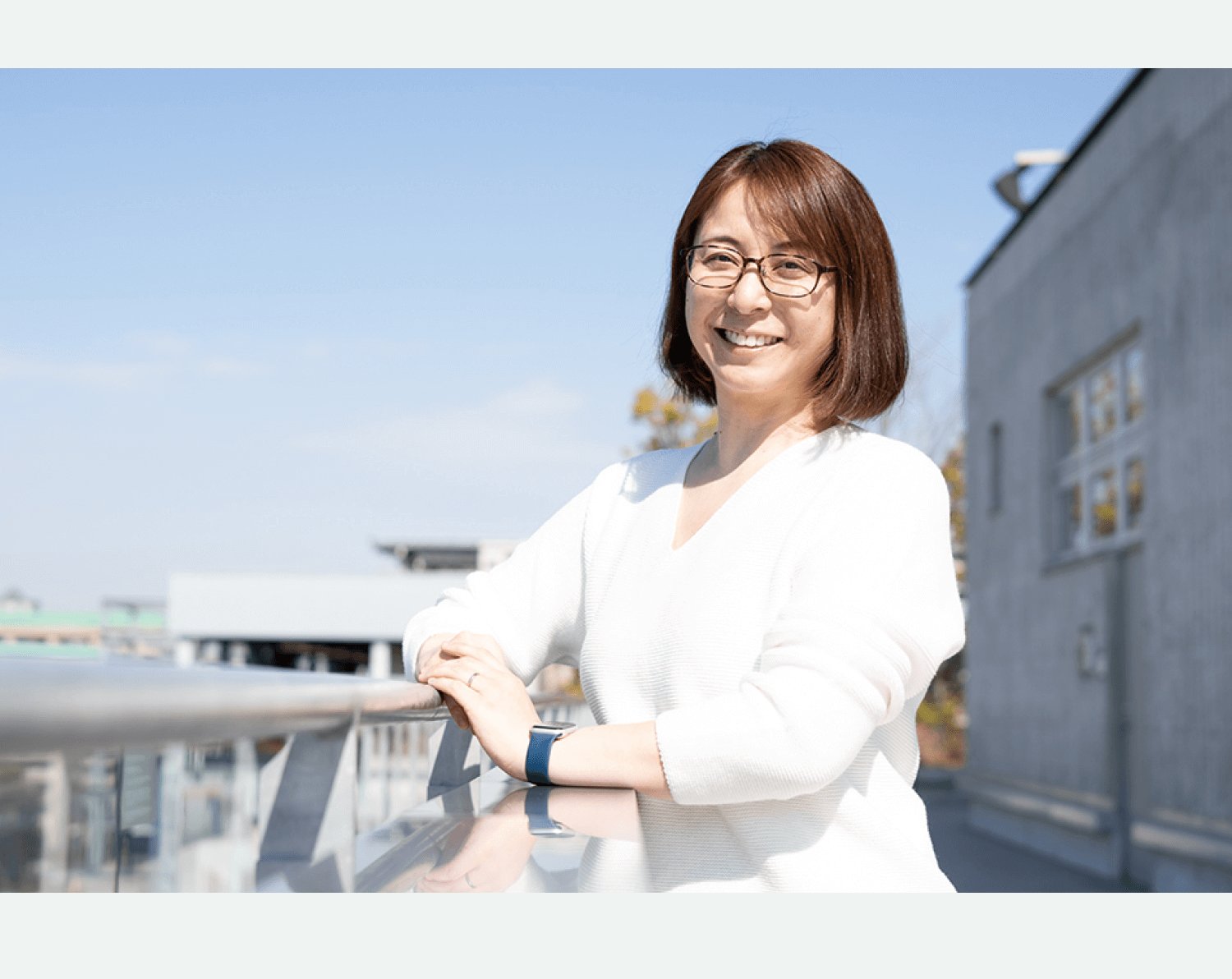ビル屋上の手すりに手をかけ微笑む美緒さん