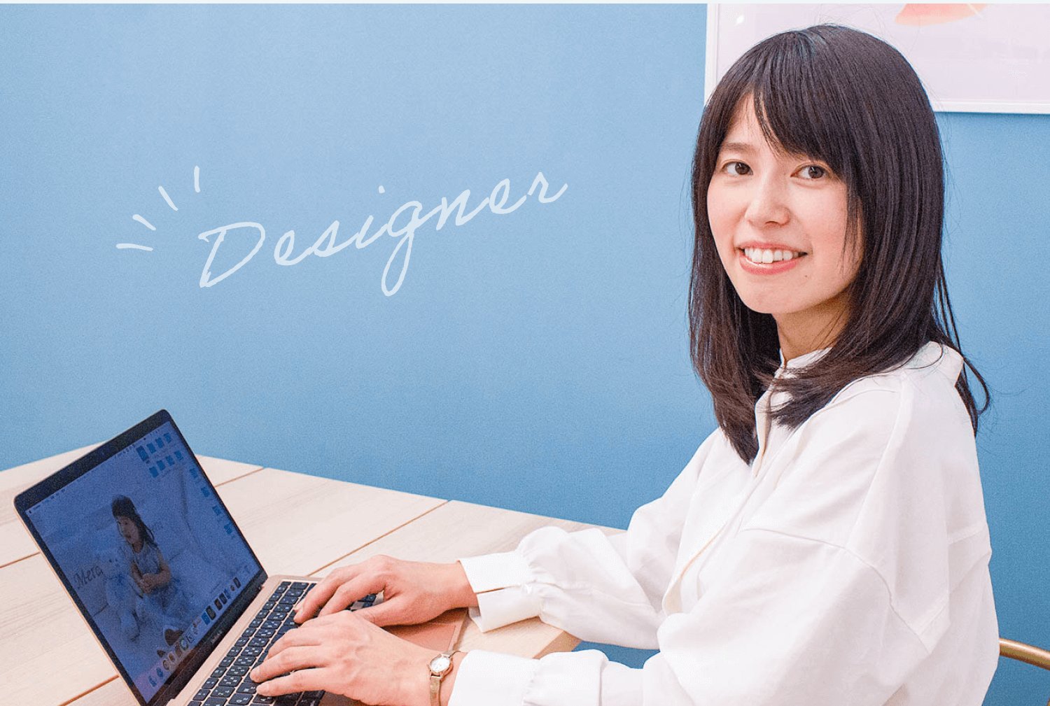 Designerの手書き文字とともに、ノートパソコンで作業する女性