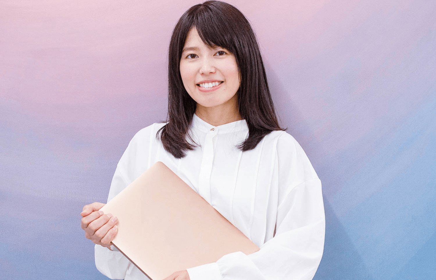 ノートパソコンを抱えて微笑む女性