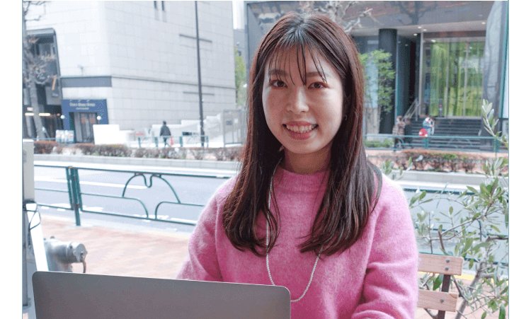 ビル街の屋外でヘッドホンをつけて微笑むyurieさん