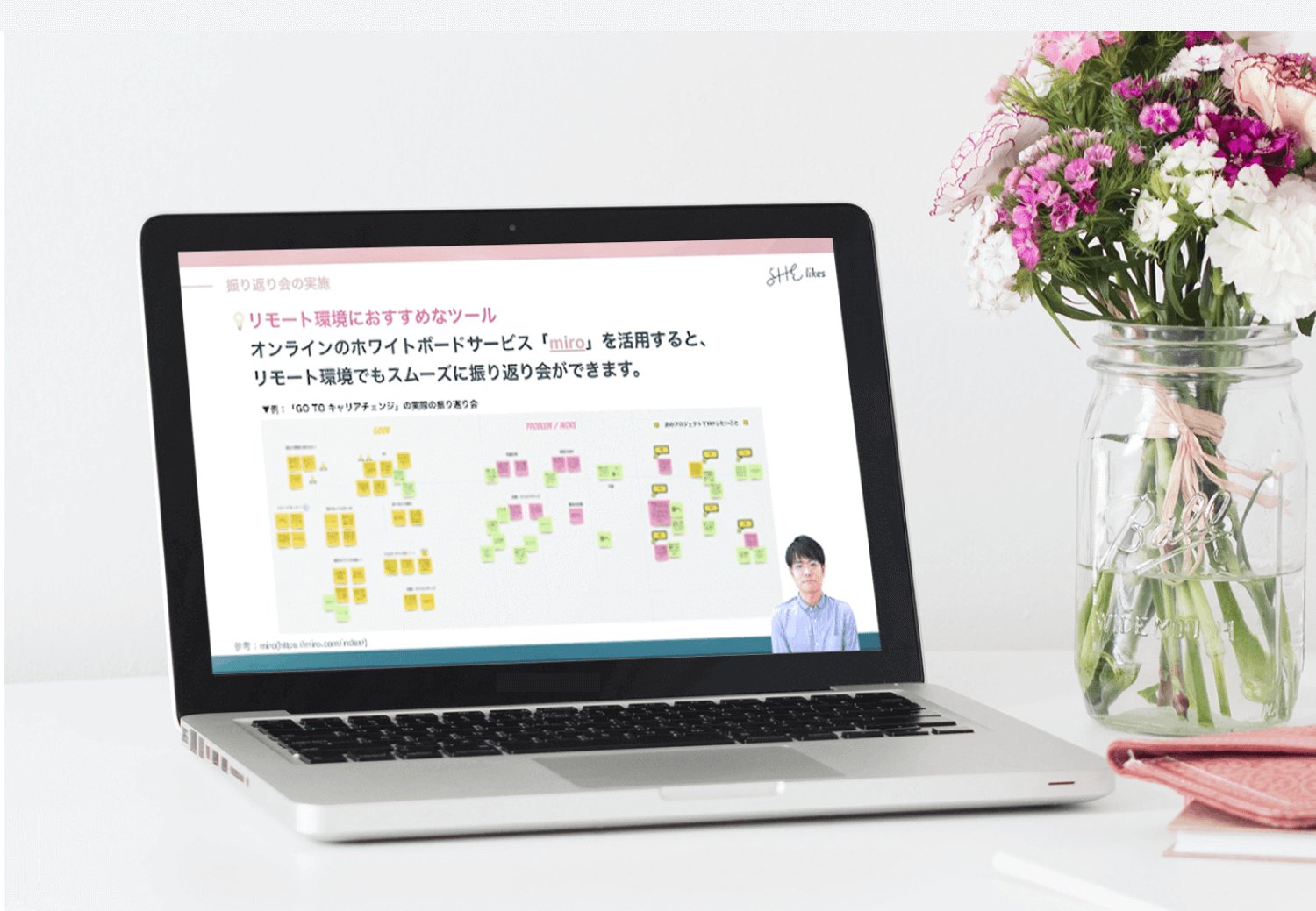 ノートパソコンの画面に振り返り会の資料を映し、隣に花を置いたデスクの様子