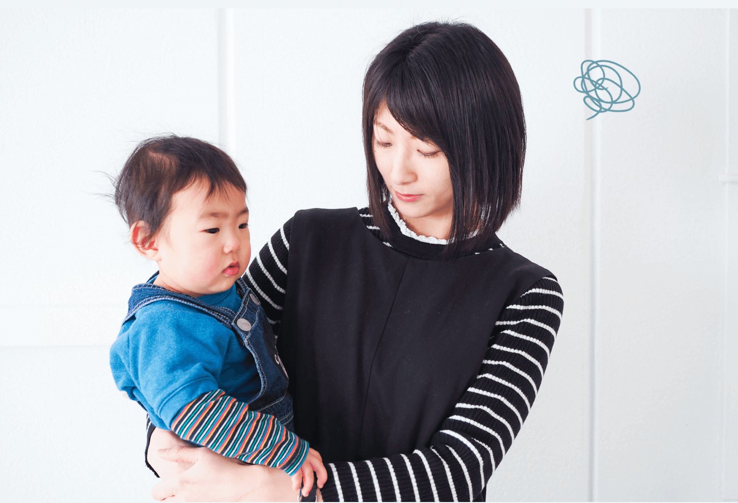 白い部屋で黒トップスのきゃんまりさんが俯き加減に子どもを抱く様子