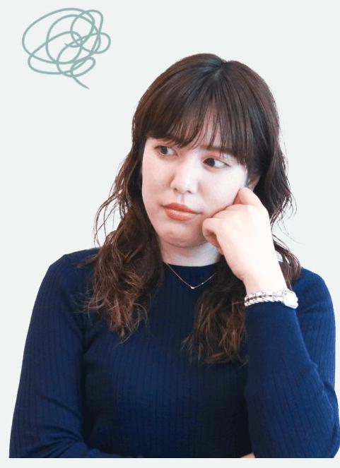 頬に手を当て考え込む紺セーターの女性（Before）