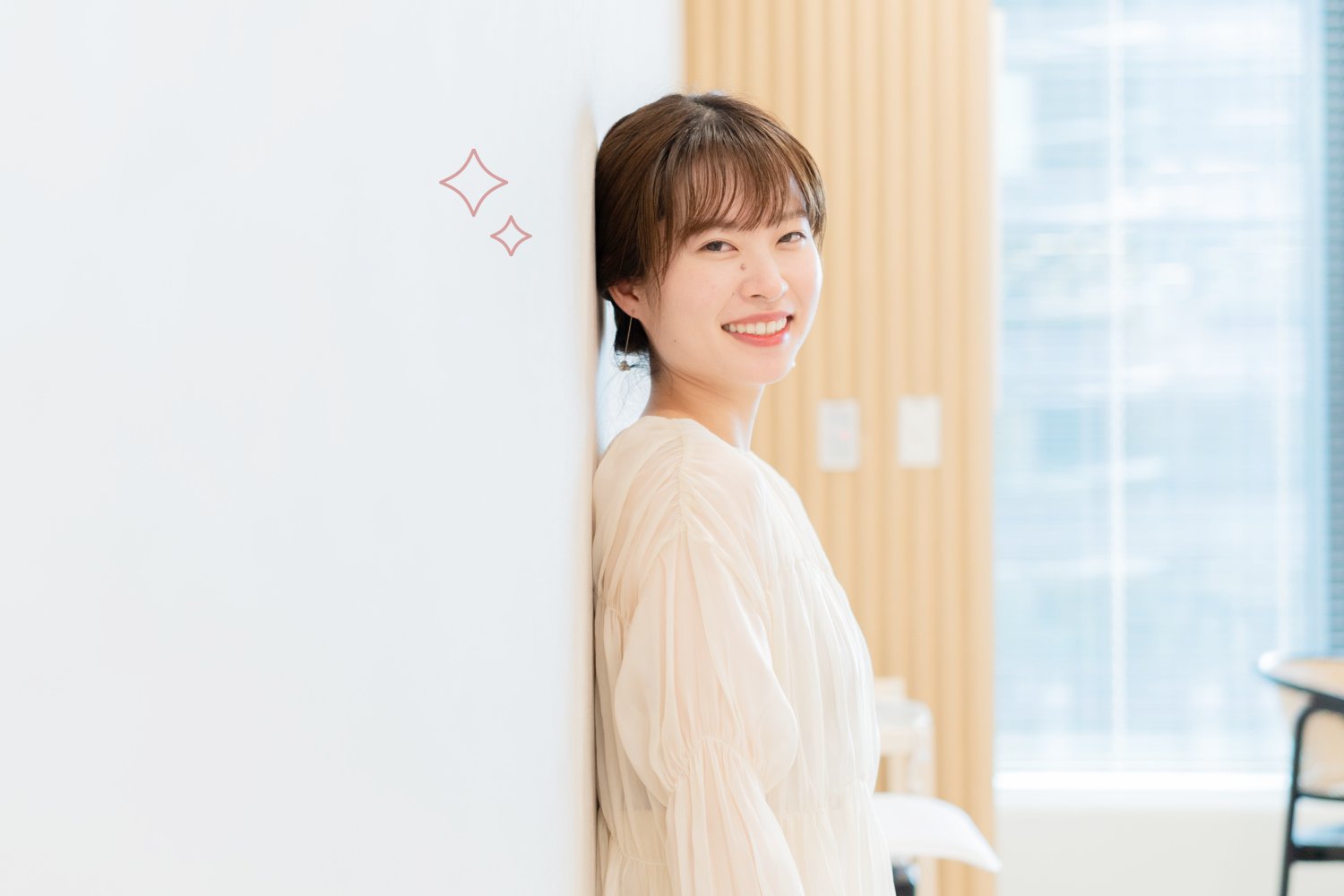 壁にもたれて微笑む女性の横顔(窓辺・オフィス背景、キラキラ装飾)