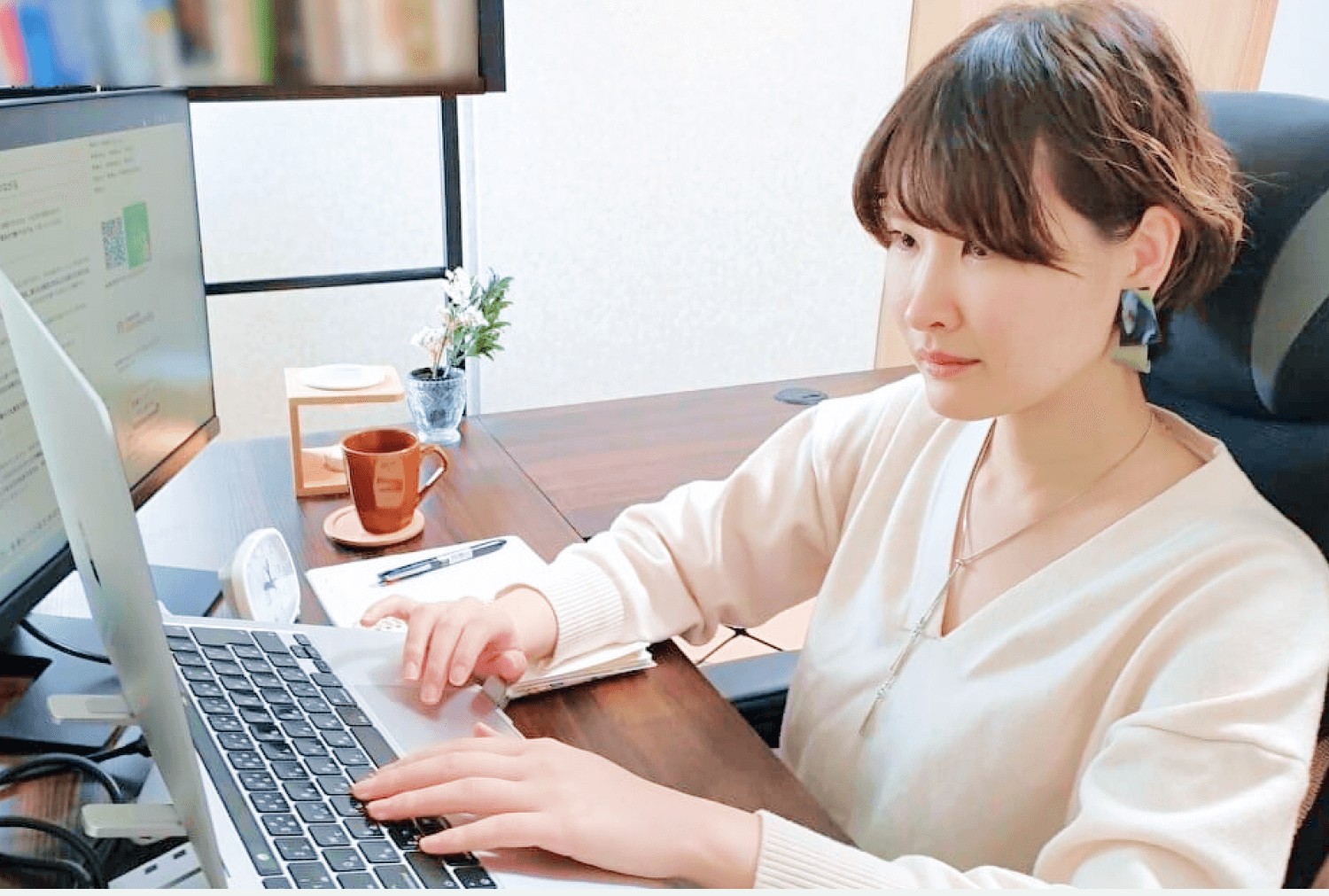 デスクでノートパソコンに向かい両手でキーボードを操作する人物