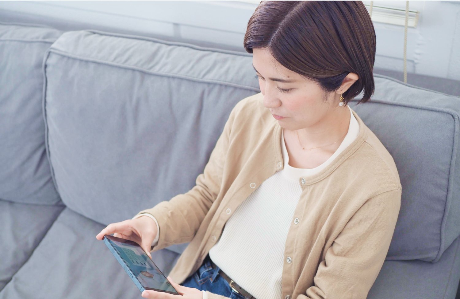 ソファでタブレットを操作する女性