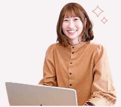 ノートパソコンを操作しながら微笑むキャメルシャツの女性（After）