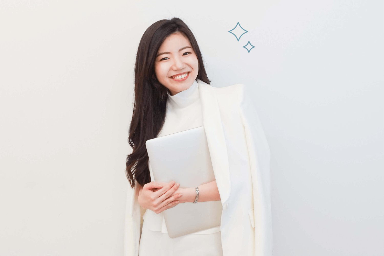 白いジャケットでノートパソコンを抱えて微笑むSakiさん