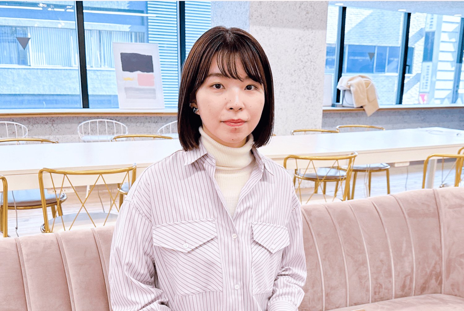 窓際のオープンスペースで、正面を向いて微笑む女性のポートレート