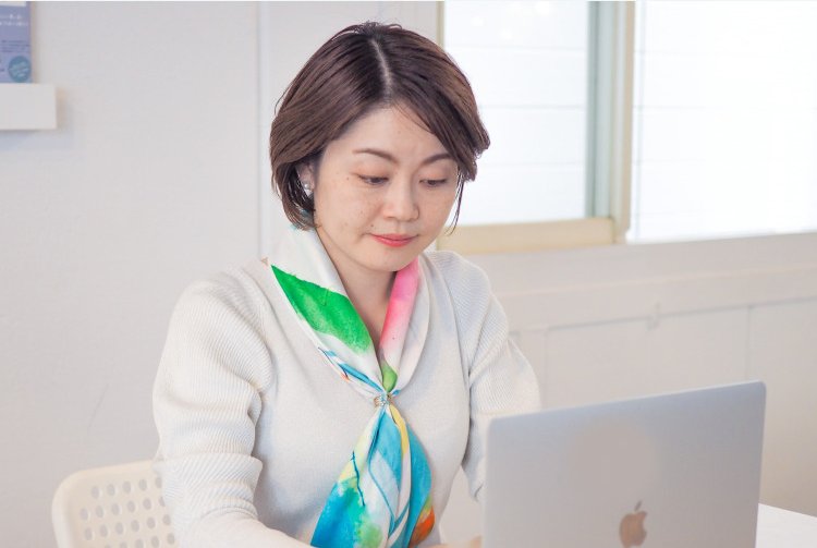 白い部屋でノートPCに向かって作業する女性