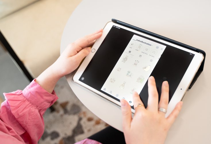タブレットで自身のイラスト投稿アカウント「kahoillustration」を表示し操作する手元
