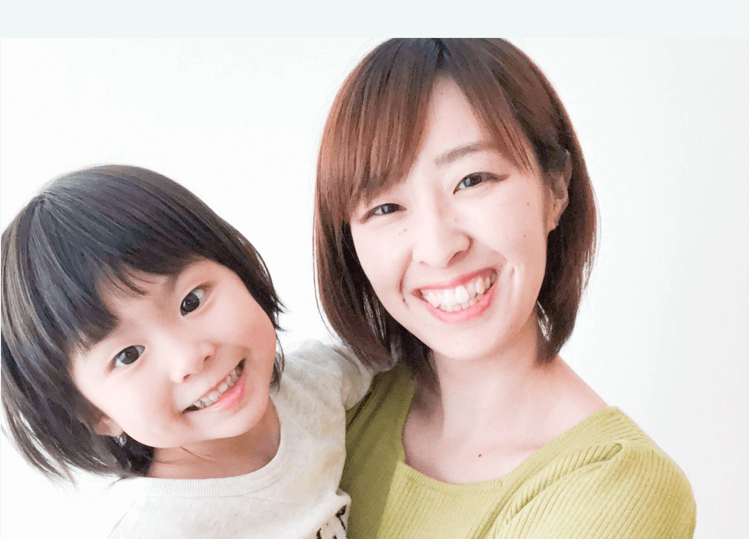 子どもと頬を寄せ合って微笑む、黄緑色トップスのsakiさんのポートレート