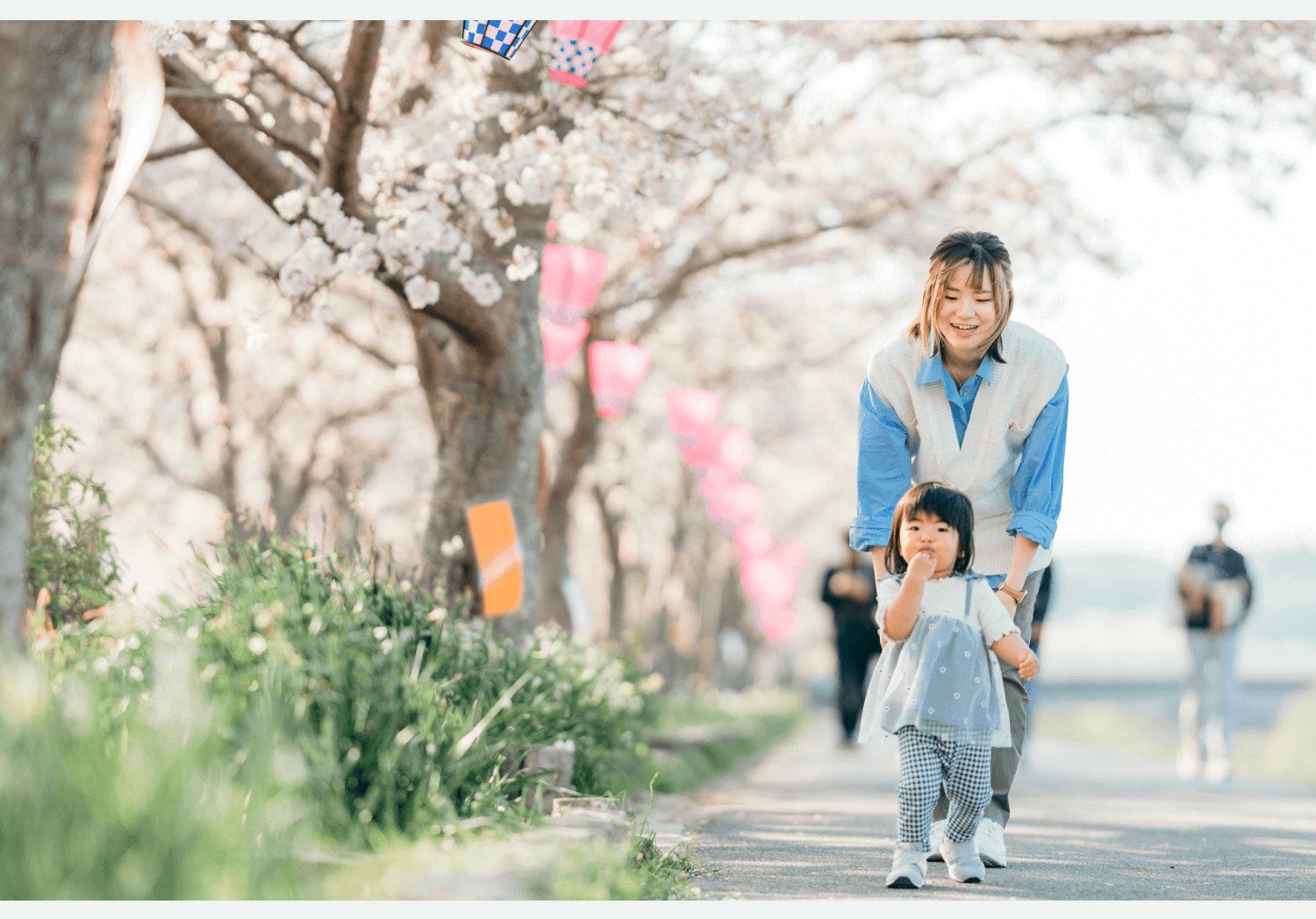桜並木の歩道で小さな子どもの手を引く彩華さん