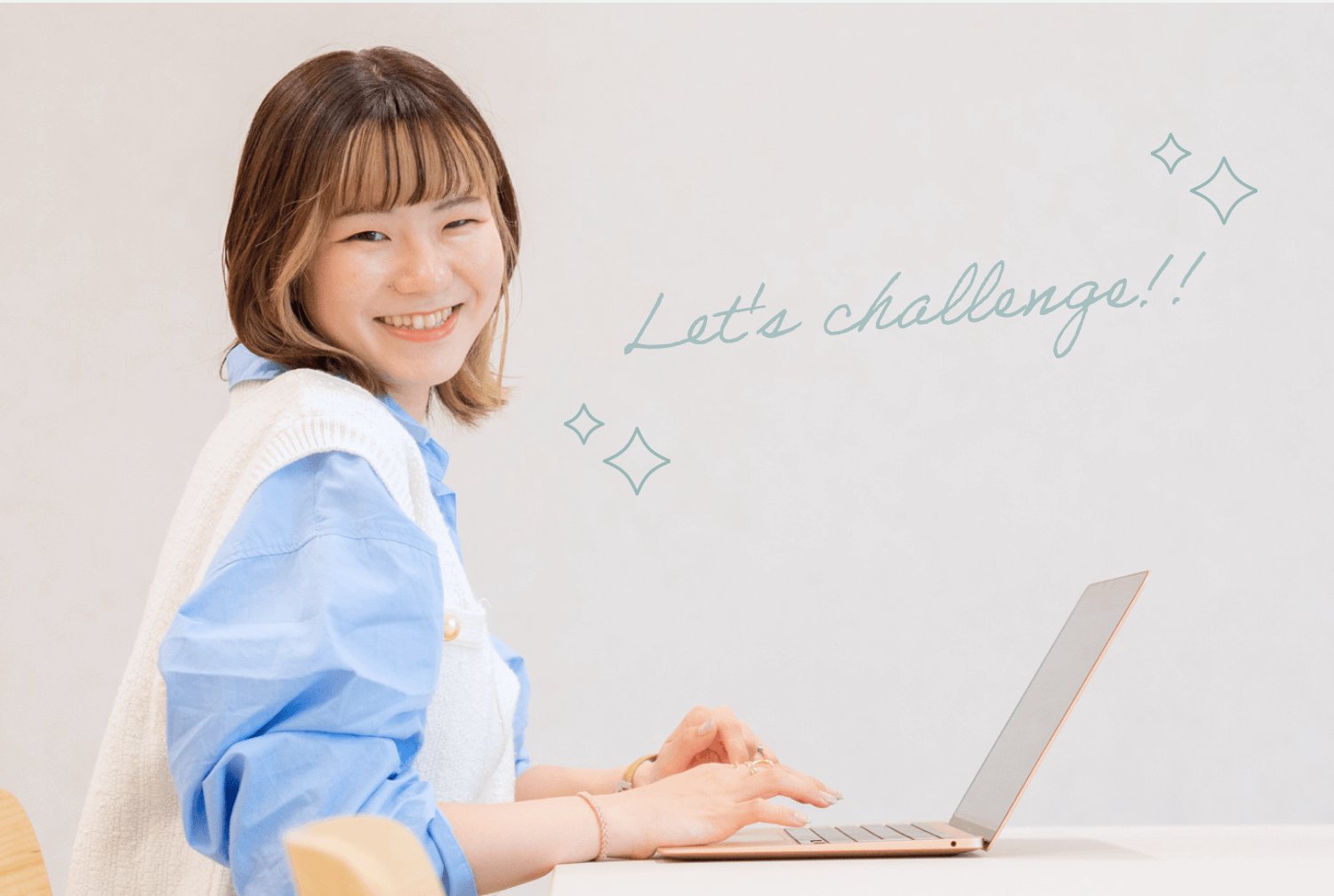 白いテーブルでノートパソコンを操作しながら振り返って微笑む彩華さん(キラキラ装飾・「Let's challenge!!」の筆記体キャプション入り)