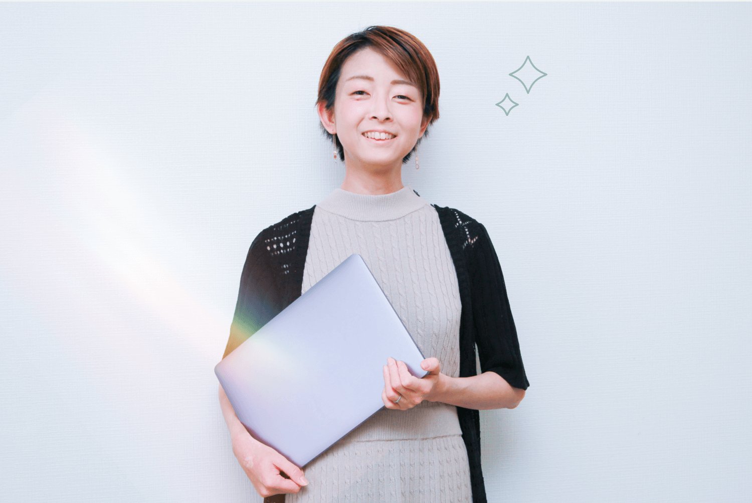 ノートPCを抱えて微笑む人物のポートレート