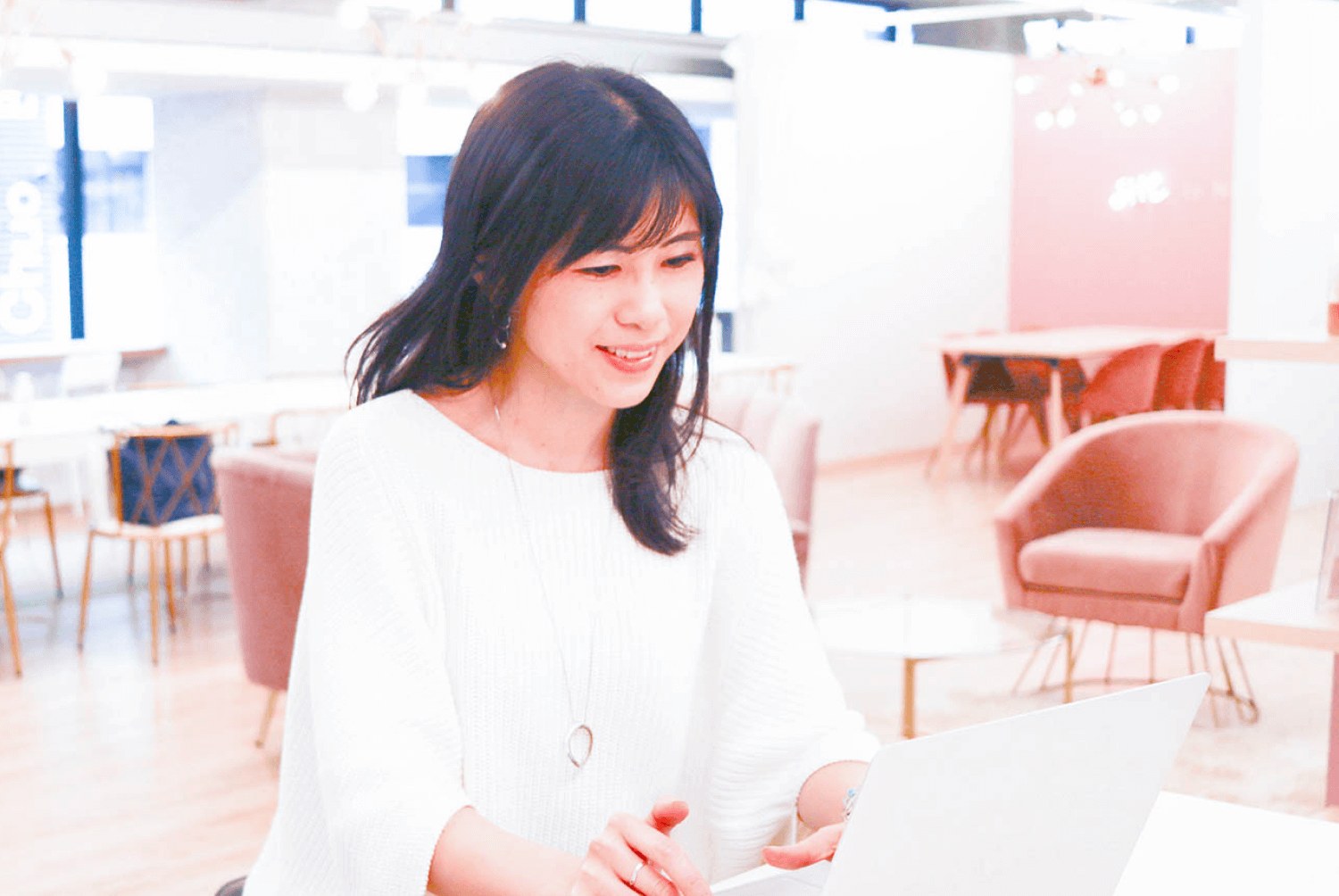 カフェラウンジで白いノートPCに向かい微笑むsatominさん