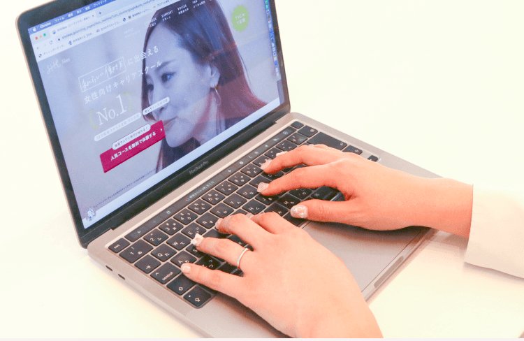 SHElikesのサイトを開いてノートPCのキーボードを操作するしおりさんの手元