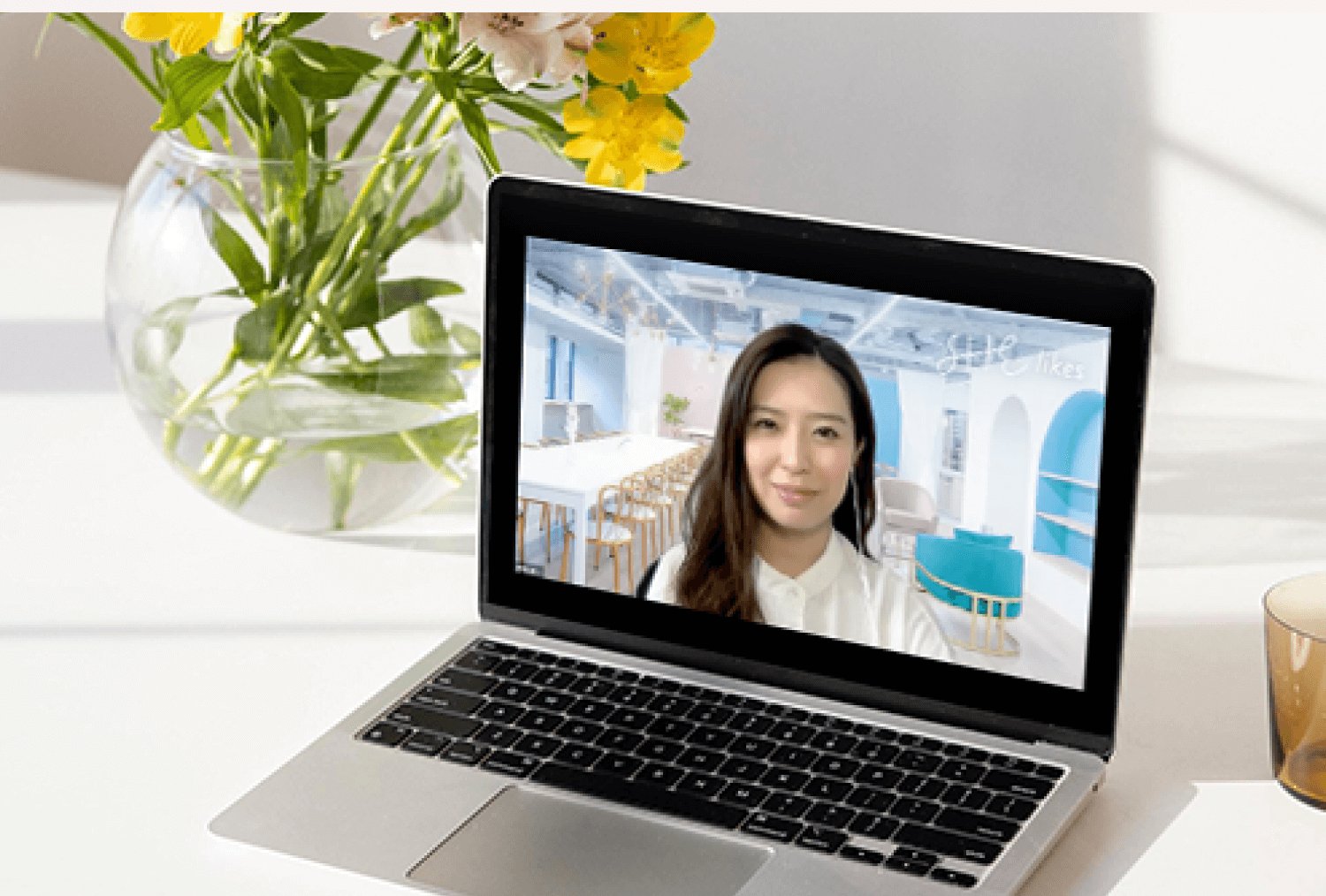 花瓶の花とノートPCの画面越しに映るコーチング担当者とのビデオ通話画面