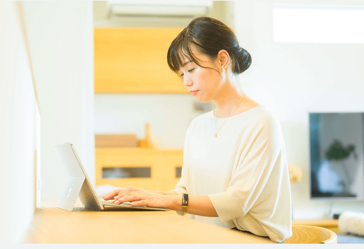 キッチンカウンターでタブレットに向かい作業するくぅこさん