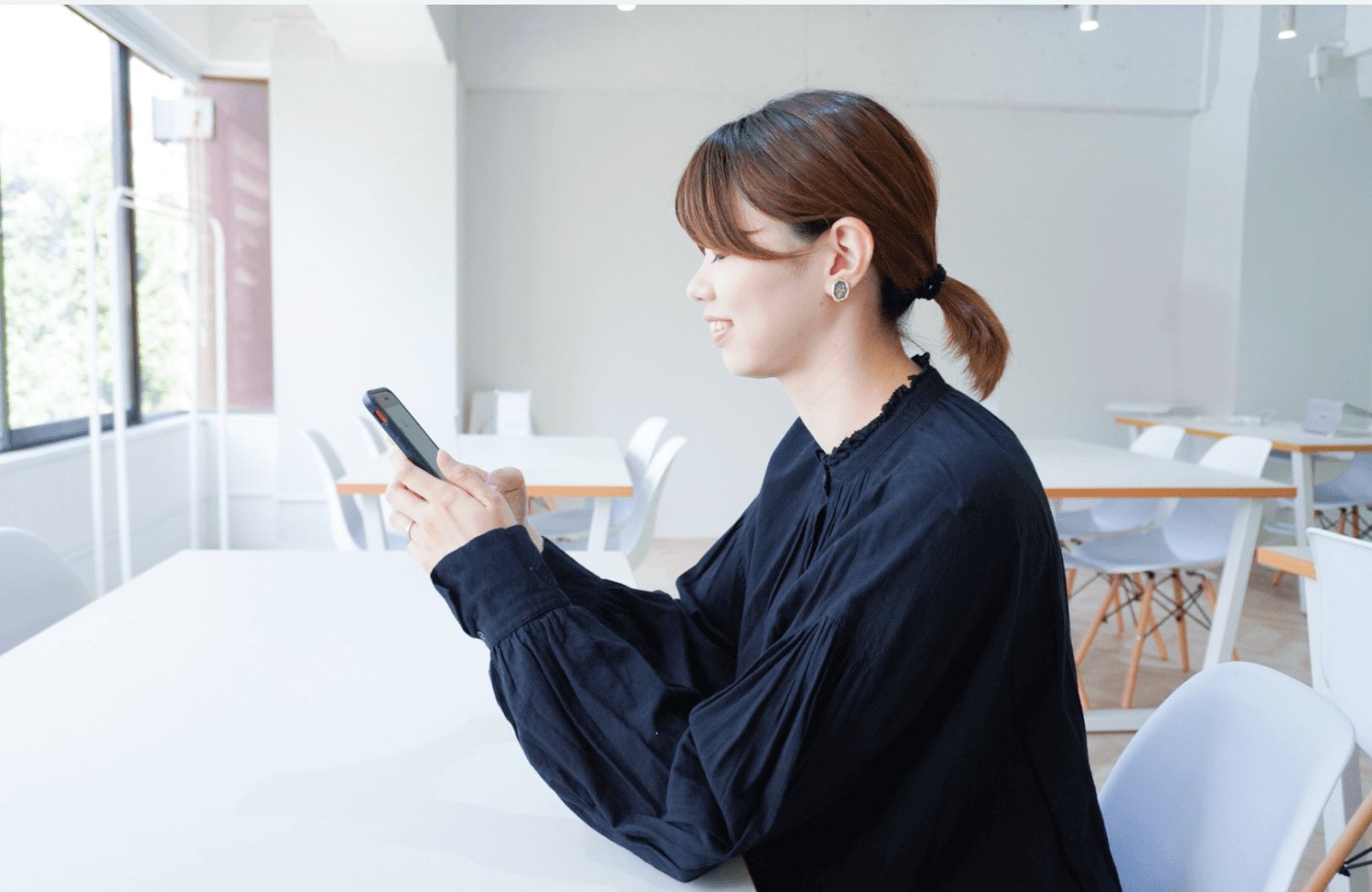 白い部屋でテーブルにつき、スマホを操作する横顔のほたてさん