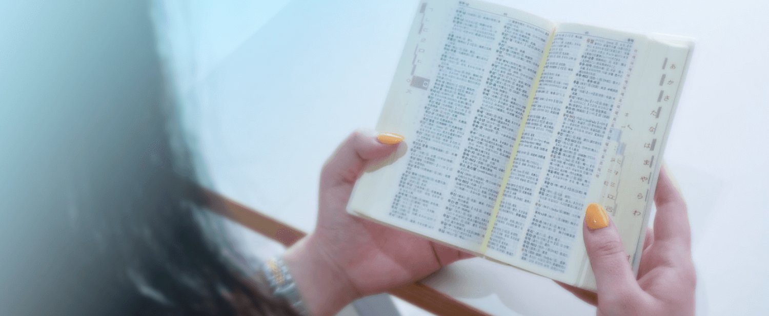 韓日辞典を両手で持って読む様子